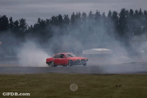 A Red Car Is Driving On A Track With Smoke Coming Out Of It GIF