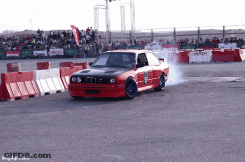 A Red Car With The Number 57 On The Side Is Driving Down A Track GIF