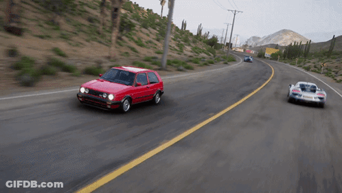 A Red Car With The Word Volkswagon On The Side Is Driving Down A Road GIF