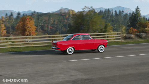 A Red Car With White Tires Is Driving Down A Road With Mountains In The Background GIF