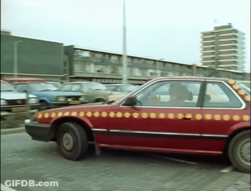 A Red Car With Yellow Circles On It Is Parked In A Parking Lot GIF