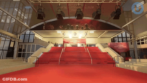 A Red Carpet Leading Up To A Stage With A Sign That Says " Cannes " GIF