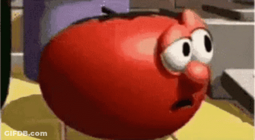 A Red Cartoon Tomato With Big Eyes And A Red Nose Is Sitting On A Yellow Table . GIF