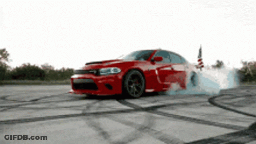 A Red Dodge Charger Is Drifting On A Concrete Surface GIF