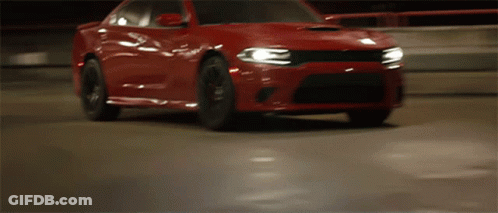A Red Dodge Charger Is Driving Down A Road At Night GIF