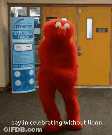 A Red Elmo Mascot Is Dancing In Front Of A Walking Track Sign GIF