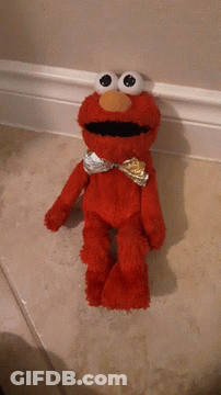 A Red Elmo Stuffed Animal Is Standing On A Tiled Floor GIF