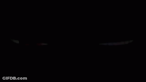 A Red Eye And A Purple Eye Are Glowing In The Dark On A Black Background . GIF