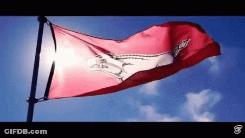 A Red Flag With A Horse On It Is Waving In The Wind Against A Blue Sky . GIF