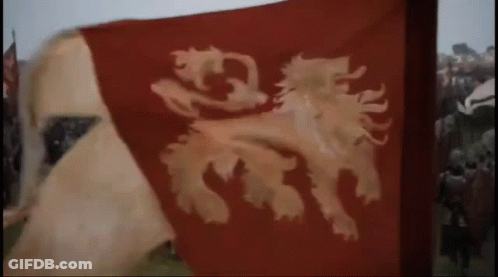 A Red Flag With A Lion On It Is Flying In The Wind In Front Of A Crowd Of People . GIF