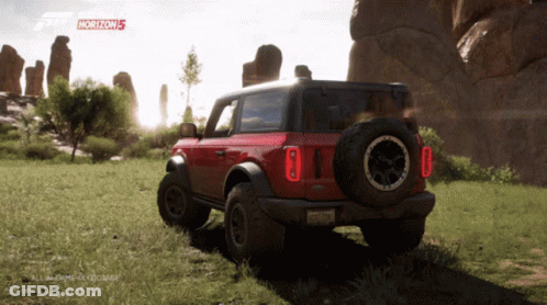 A Red Ford Bronco Is Parked In A Grassy Field With Horizon 5 Written On The Screen GIF