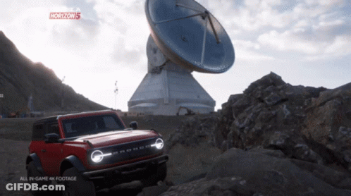 A Red Ford Bronco Is Parked In Front Of A Large Antenna In A Video Game Called Horizon 5 GIF