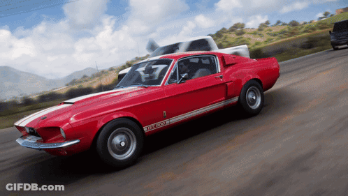 A Red Ford Mustang Gt500 Is Driving Down The Road GIF