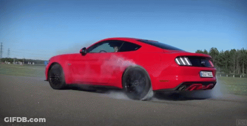 A Red Ford Mustang Is Driving Down A Road With Smoke Coming Out Of It GIF