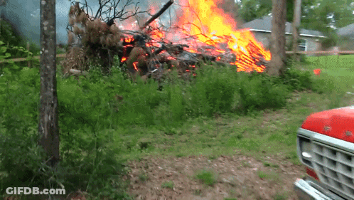 A Red Ford Truck Is Parked In Front Of A Large Pile Of Fire GIF