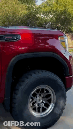 A Red Gmc Truck Is Parked On The Side Of A Road GIF