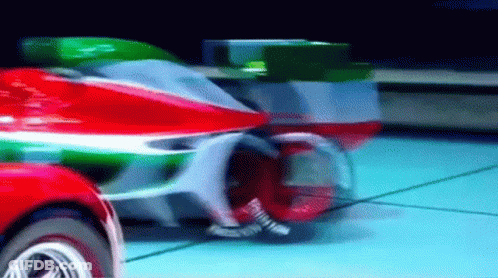 A Red , Green , And White Motorcycle Is Driving Down A Road . GIF