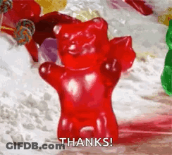 A Red Gummy Bear Is Standing In Front Of A Pile Of Other Gummy Bears . GIF