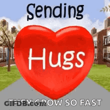 A Red Heart With The Words `` Sending Hugs They Grow So Fast '' Written On It Is Sitting On A Sidewalk . GIF