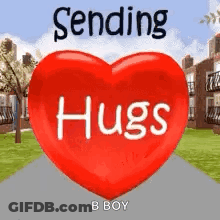 A Red Heart With The Words `` Sending Hugs '' Written On It Is Sitting On A Sidewalk . GIF