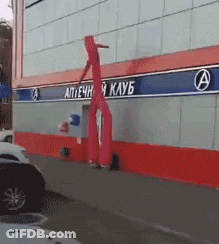A Red Inflatable Person Is Standing In Front Of A Building With The Letter A On It GIF