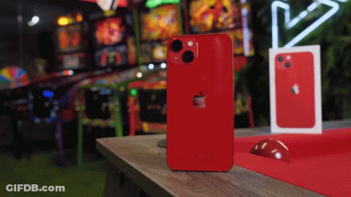 A Red Iphone Is Sitting On A Table In Front Of An Arcade GIF