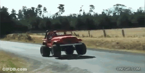 A Red Jeep Is Driving Down A Road Next To A Field GIF