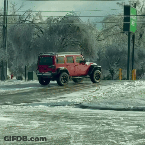 A Red Jeep Is Driving Down A Snowy Road In Front Of A Green Sign GIF