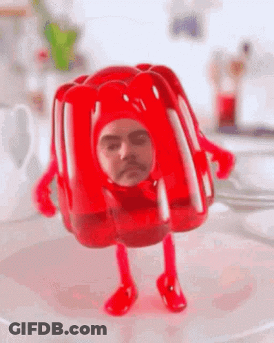 A Red Jelly With A Man 'S Face On It Is Standing On A White Plate . GIF