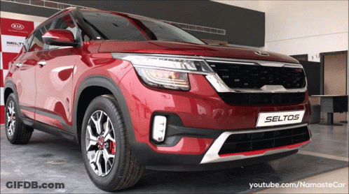 A Red Kia Seltos Is On Display At A Kia Dealership GIF