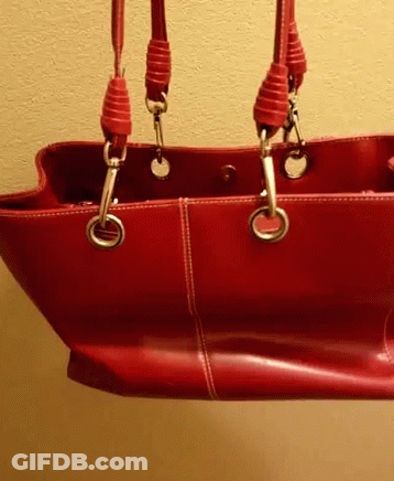 A Red Leather Purse With Two Handles Is Hanging From A Wall GIF