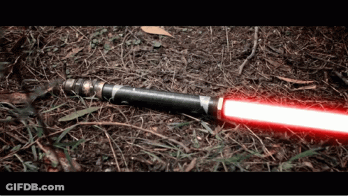 A Red Light Saber Is Laying On The Ground In The Dirt GIF
