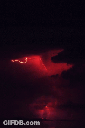 A Red Lightning Bolt Strikes The Ground In The Night Sky GIF