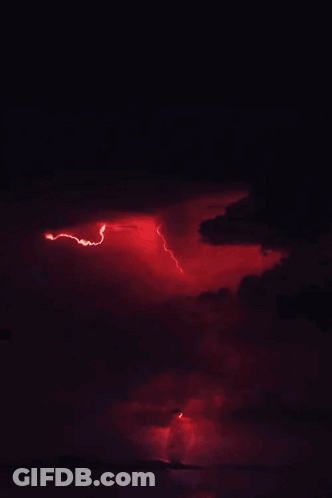 A Red Lightning Bolt Strikes Through The Clouds In The Night Sky GIF