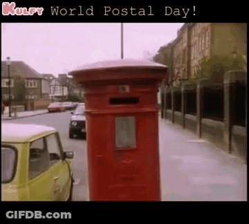 A Red Mailbox On The Side Of A Street With The Words Kulfy World Postal Day Below It GIF