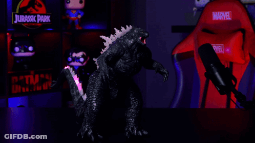 A Red Marvel Chair Sits In Front Of A Glowing Godzilla Figure GIF