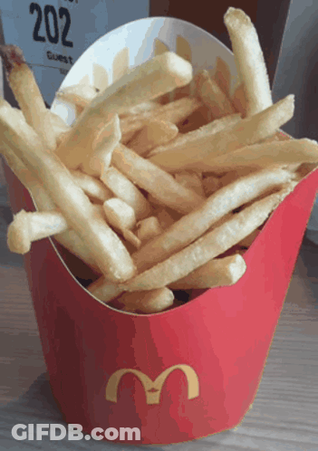 A Red Mcdonald 'S Box Filled With French Fries Sits On A Table GIF