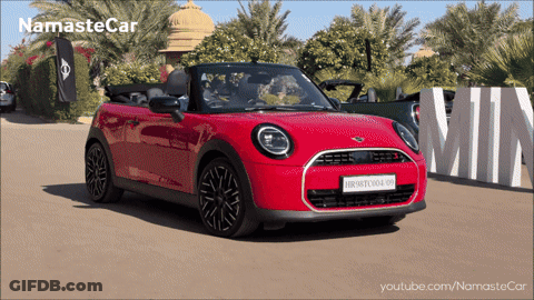A Red Mini Convertible Is Parked In Front Of A Sign That Says Min GIF