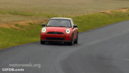 A Red Mini Cooper Is Driving Down A Curvy Road With Motorweek.org Written On The Bottom GIF