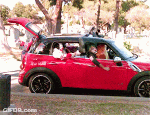 A Red Mini Cooper With A Clown In The Driver 'S Seat GIF