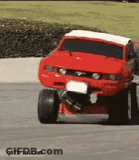 A Red Monster Truck Is Driving Down A Road With A Gifbin.com Watermark At The Bottom GIF