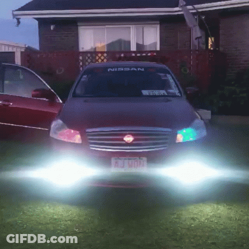 A Red Nissan Car Is Parked In Front Of A Brick House GIF
