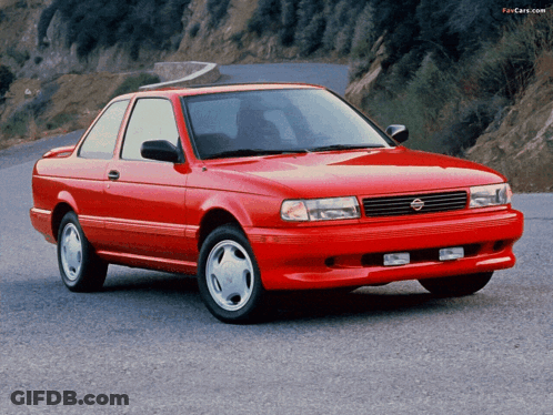 A Red Nissan Is Parked On The Side Of A Road GIF