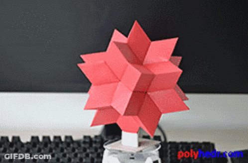 A Red Origami Object Is Sitting On A Table Next To A Keyboard GIF