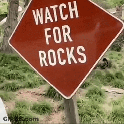 A Red Sign Says Watch For Rocks On It GIF
