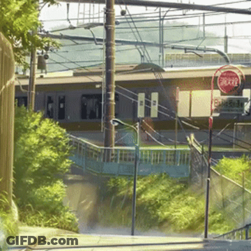 A Red Sign That Says Stop On It In Front Of A Train Station GIF