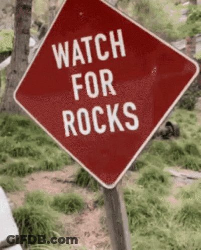 A Red Sign That Says Watch For Rocks GIF