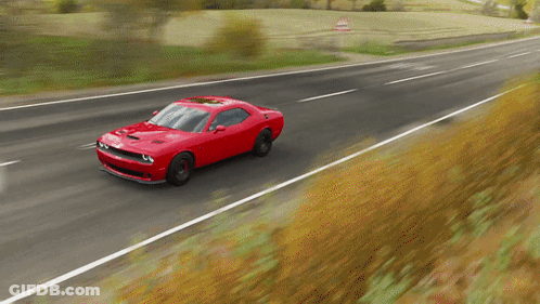 A Red Sports Car Is Driving Down A Road GIF
