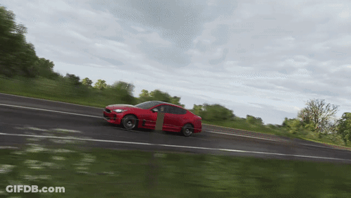 A Red Sports Car Is Driving Down A Road GIF