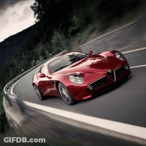A Red Sports Car Is Driving Down A Road GIF